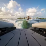 male wake surfing wave behind boat at sea
