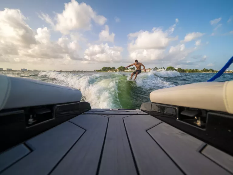 male wake surfing wave behind boat at sea